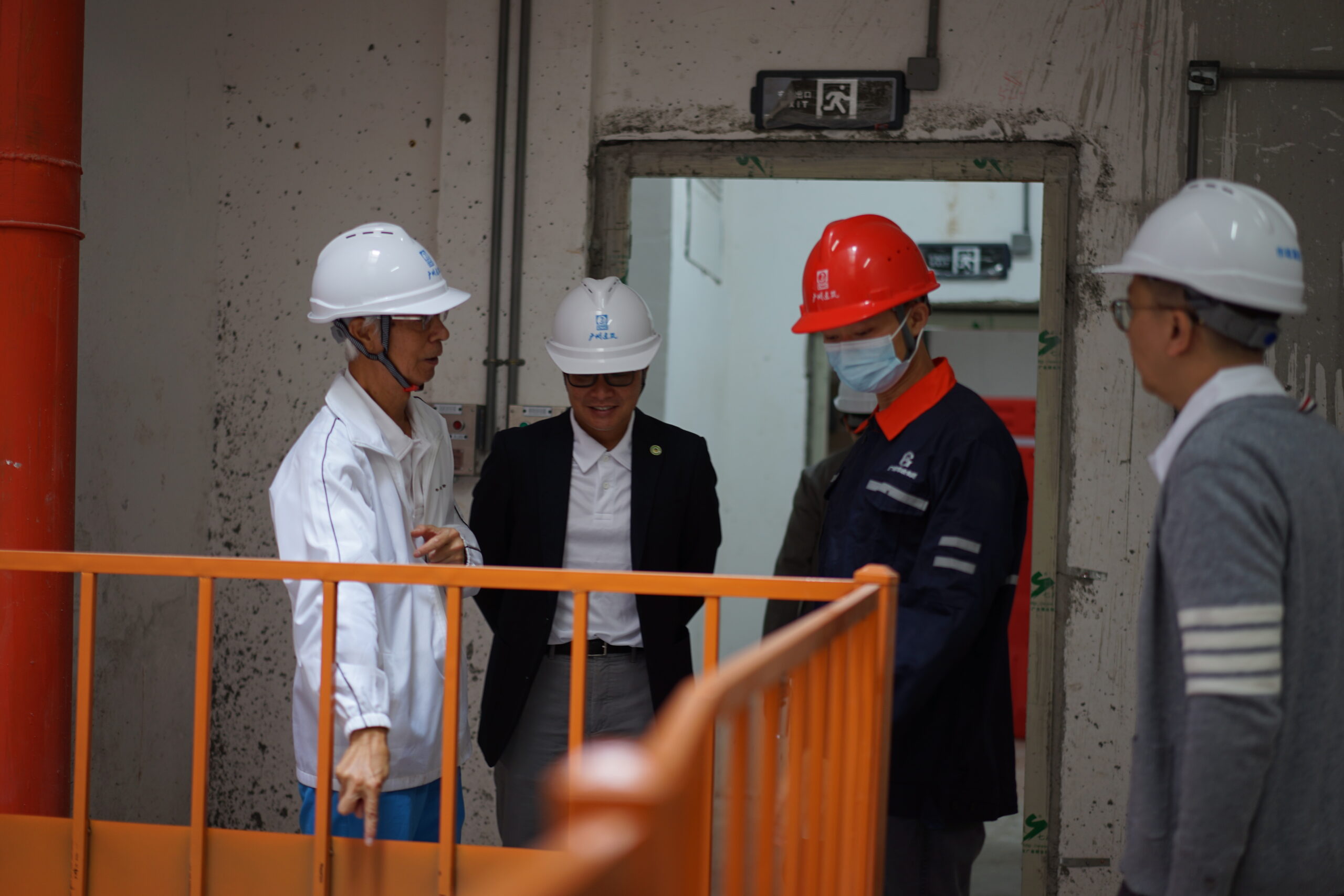 義務司庫梁健忠先生(左)向工程項目的負責員工(紅帽)查詢管道下層的結構